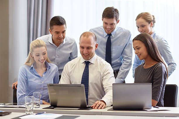 istock smiling businesspeople with laptops in office 466472664