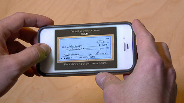 Deposit Check with Cell Phone Depositing a check with a mobile phone. Check and phone interface are both fictional. financial bill photos stock pictures, royalty-free photos & images