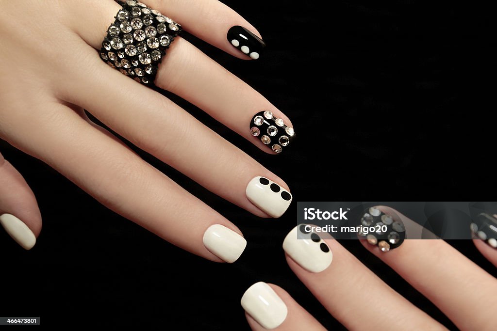 Manicure on short nails. Manicure on short nails covered with black and white lacquered with rhinestones on a black background. Adult Stock Photo