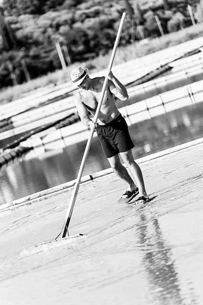 Man working with showel at salt pans. Black and white image.