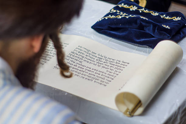 Purim in Jerusalem Jerusalem, Israel - March 5, 2015: An ultra-orthodox Jew reads the book of Esther (the megillah), as part of the traditions of the holiday of Purim, in Jerusalem, Israel esther bible stock pictures, royalty-free photos & images