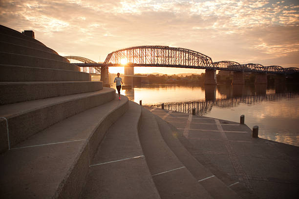 kobieta działa wzdłuż rzeki w centrum miasta cincinnati, w stanie ohio. - orange ohio zdjęcia i obrazy z banku zdjęć