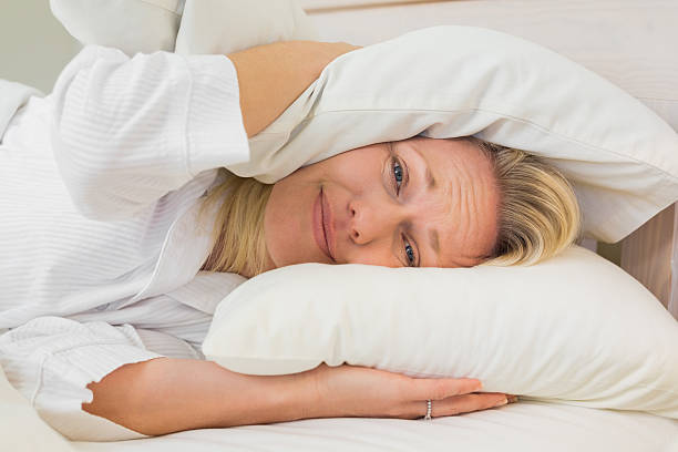 istock Irritated woman covering ears with pillows 466496664