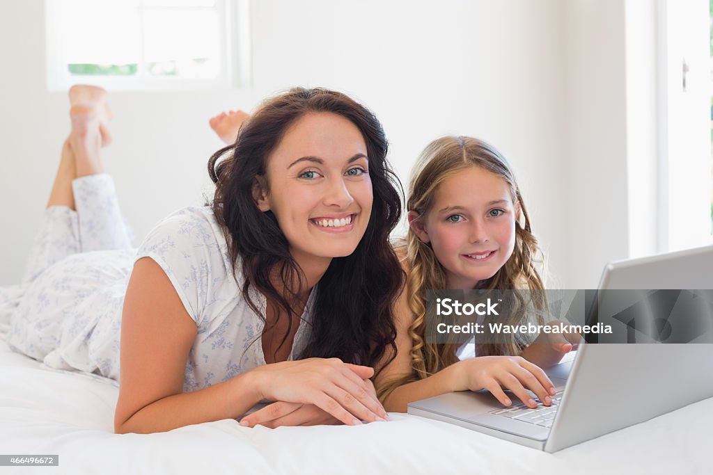 Mother and daughter with laptop lying in bed Portrait of mother and daughter with laptop lying in bed at home 20-29 Years Stock Photo
