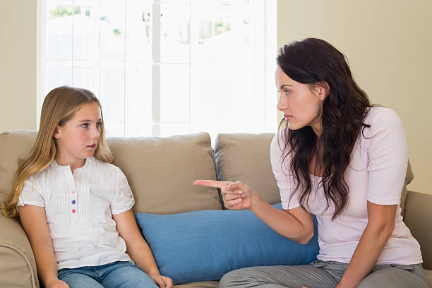 istock Mother scolding girl while sitting on sofa 466497286