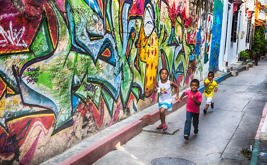 Cartagena, Colombia - February 23, 2014: Local children run through the colorful streets of Cartagena's Getsemani neighborhood.