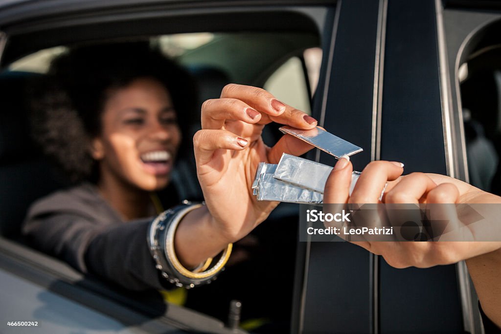 Women passing chewing gum out of the window car Women passing chewing gum out of the window's car during a road trip. Bubble Gum Stock Photo