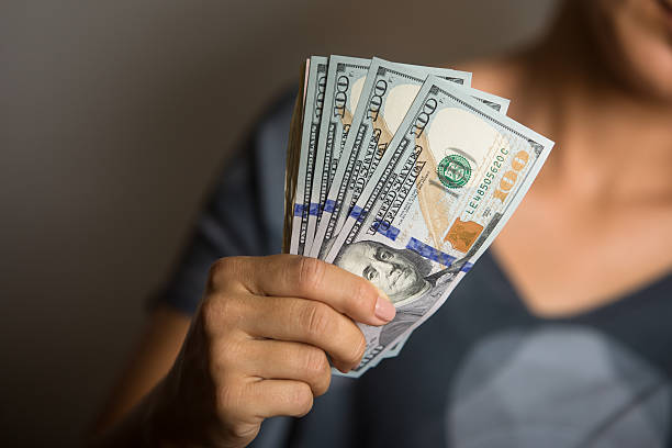 istock Woman holding notes of one hundred US dollars. 466501554