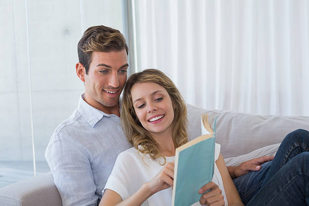 istock Young couple reading book on couch 466502578