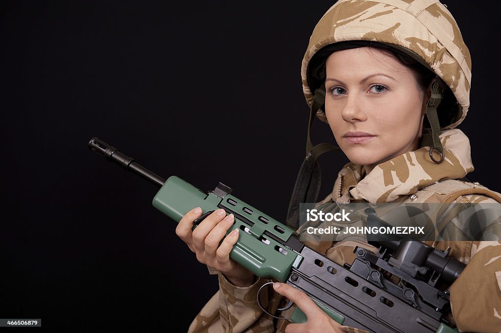 Army Girl With Rifle Portrait of a young female British soldier with her SA80 rifle against a black background. Adult Stock Photo