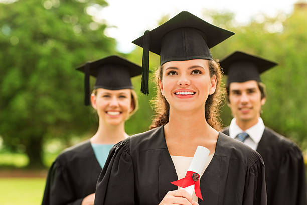 istock Girl Holding Diploma Looking Away With Students In Background 466507491
