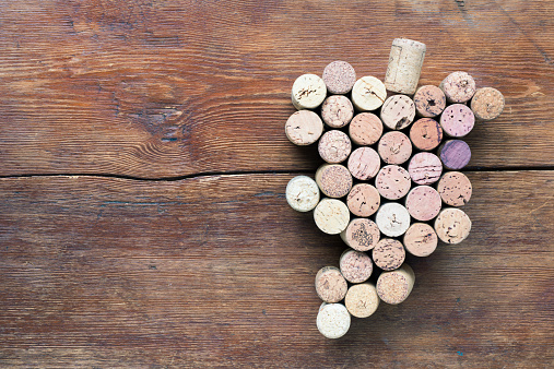 many wine corks arranged in shape of grape bunch on wooden table background