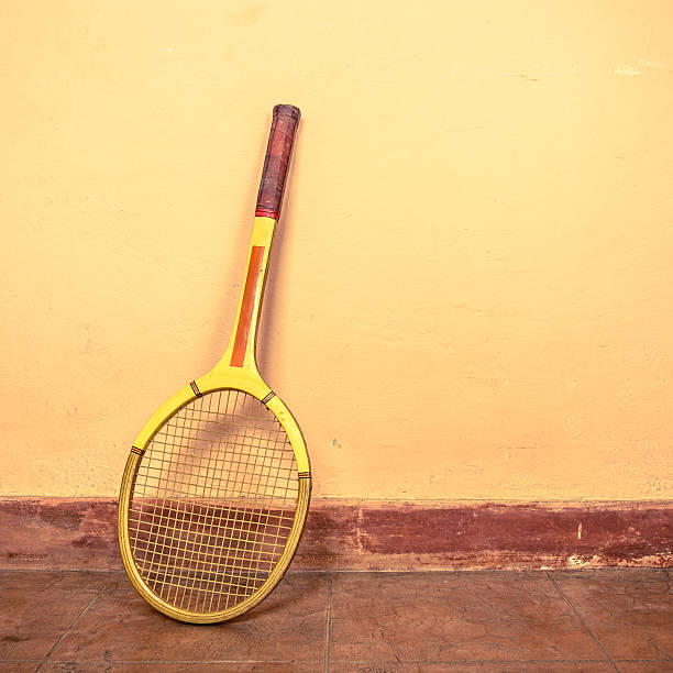 Vintage tennis racket leaning up against a wall