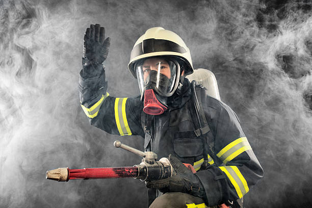 Firefighter in full gear battling smoke stock photo