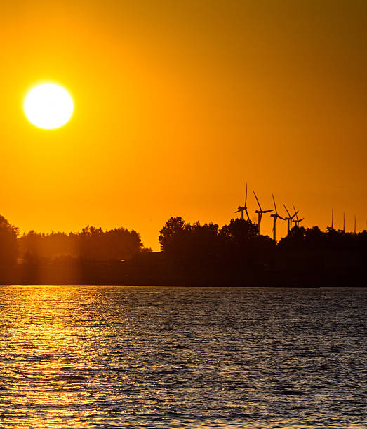 istock Large windmills with the sun reflecting on water 466523117