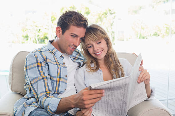 istock Happy couple reading newspaper on couch 466523474
