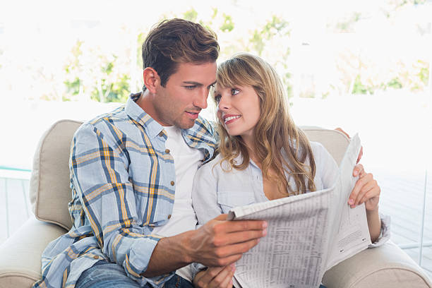 istock Loving happy couple reading newspaper on couch 466523504