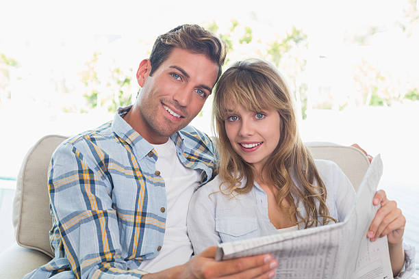 istock Loving happy couple reading newspaper on couch 466523514