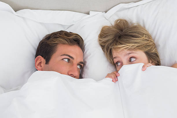 détendue jeune couple dans un lit - couple affectionate relaxation high angle view photos et images de collection