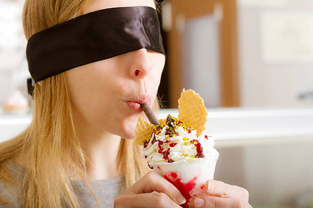 blindfolded mujer joven degustación de helado - spoon tasting women sex symbol fotografías e imágenes de stock