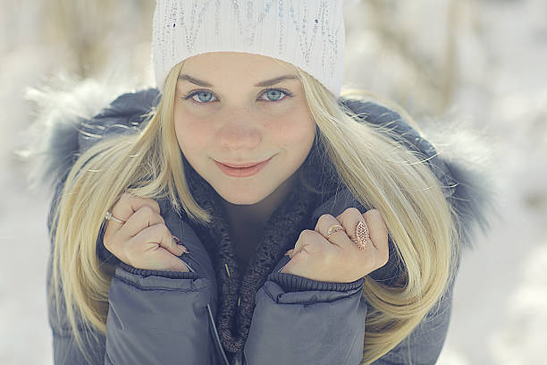 Portrait of beautiful young woman in white fur hood in winter day