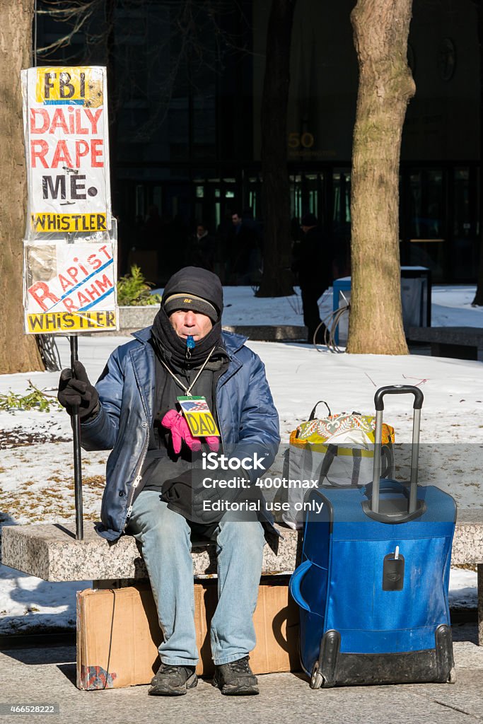 Protestor Chicago, USA - January 27, 2015: A man on West Washington Street in downtown blowing a whistle holding a sign that reads FBI Daily Rape Me late in the day.  Cold Temperature Stock Photo