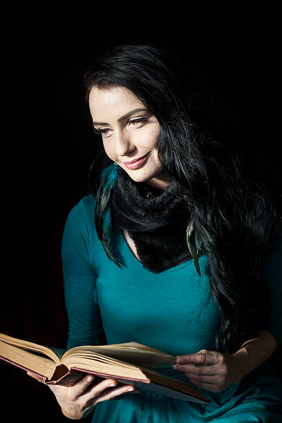 linda mulher a ler um livro em fundo preto - hardbound imagens e fotografias de stock