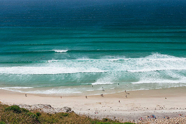 Views over Fistral Beach, Newquay, Cornwall on a bright sunny June day, people surfing and enjoying the beach. Medium format camera.