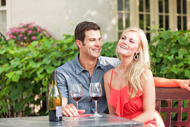 Young Lovers Enjoying Glass of Wine in Outdoor Restaurant Hz Subject: Young romantic couple on vacation in outdoor wine bar restaurant. wine bar counter stock pictures, royalty-free photos & images