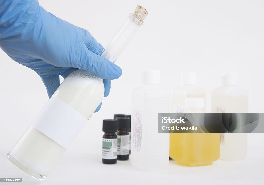 Laboratorium z butelki oleju i Ręka w niebieskie rękawice - Zbiór zdjęć royalty-free (Biały)