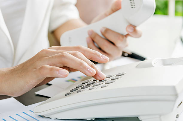 Dialling on a telephone Woman dialling on a telephone in an office dialling phone stock pictures, royalty-free photos & images