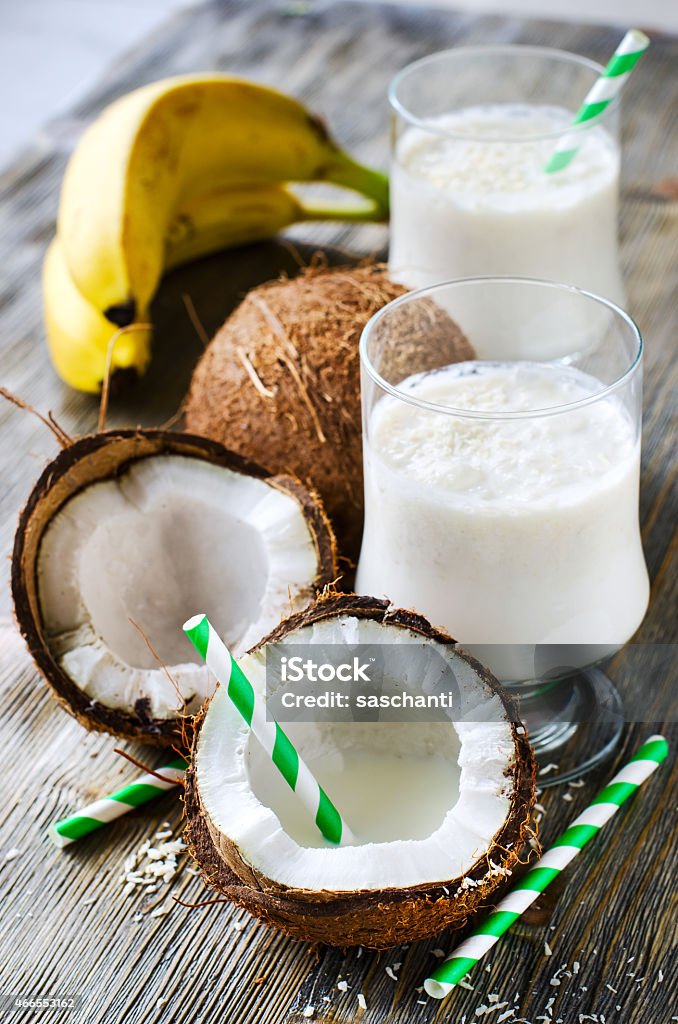 Coconut tropical smoothie drink with bananas on wooden backgroun Fresh sweet healthy coconut milk shake with bananas vertical 2015 Stock Photo