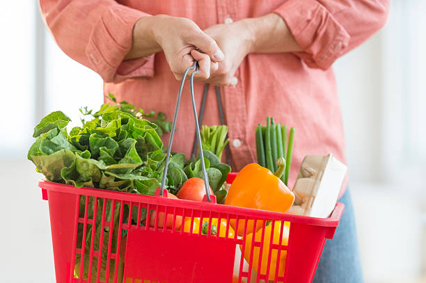 A man carrying a red basket full of vegetables Midsection of mature man carrying basket full of vegetables at home holding shopping basket stock pictures, royalty-free photos & images