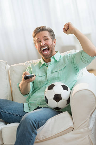 istock Excited Man Watching Soccer Match On Sofa 466554551