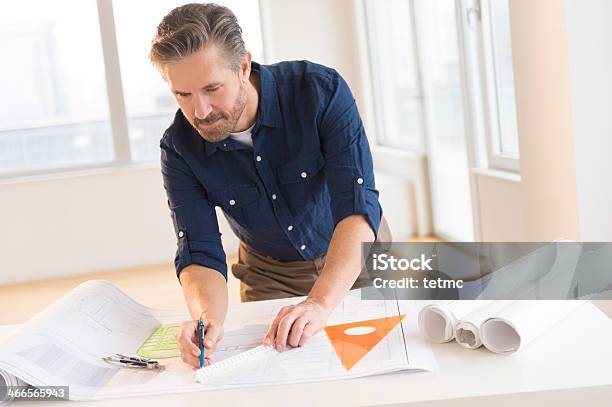 Architect Working On Blueprint At Office Desk Stock Photo - Download Image Now - Architect, 50-59 Years, 55-59 Years