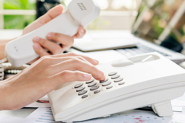 Dialling on a telephone Woman dialling on a telephone in an office dialling phone stock pictures, royalty-free photos & images