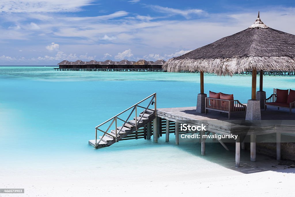 Over water jetty with steps into tropical lagoon Over water jetty with steps into tropical blue lagoon Maldives Stock Photo