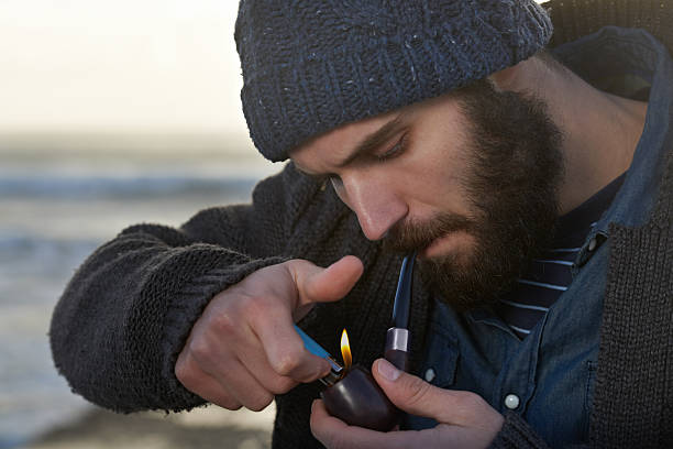 Cropped shot of a bearded man smoking a pipe outside