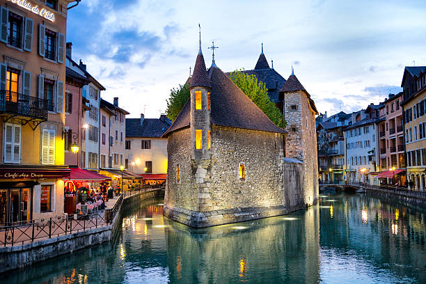 Famous Palais de L'Isle, Spring Evening, Annecy, France Annecy, France - April 26, 2010: The Palais de L'Isle sits in the middle of the Canal du Thiou connecting with the Lake of Annecy.  Annecy is located 35 km south of Geneva, and at one time was part of Geneva's administrative region.  The Palais dates from the 14th century, and has been a residence, courthouse, mint, prison and museum over the centuries.  It has also been part of the administration of Haute Savoie. Today it hosts exhibits on local architecture and history. In the evening, it's lighting casts reflections in the water of the canal flowing around it. circa 14th century stock pictures, royalty-free photos & images