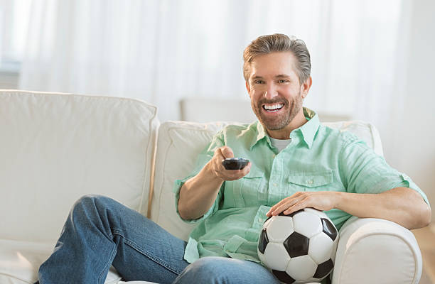istock Man With Soccer Ball Watching TV 466579267