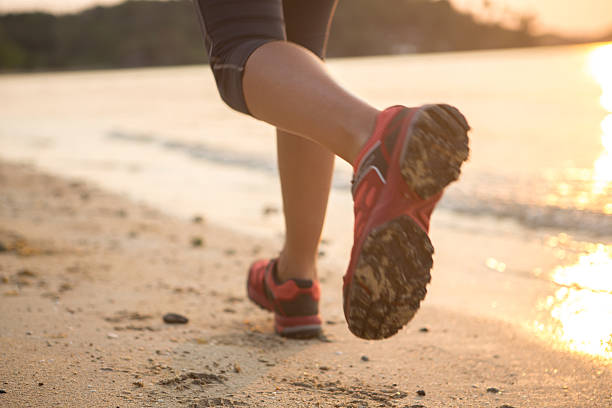 laufen am strand bei sonnenuntergang - human foot running jogging human leg stock-fotos und bilder