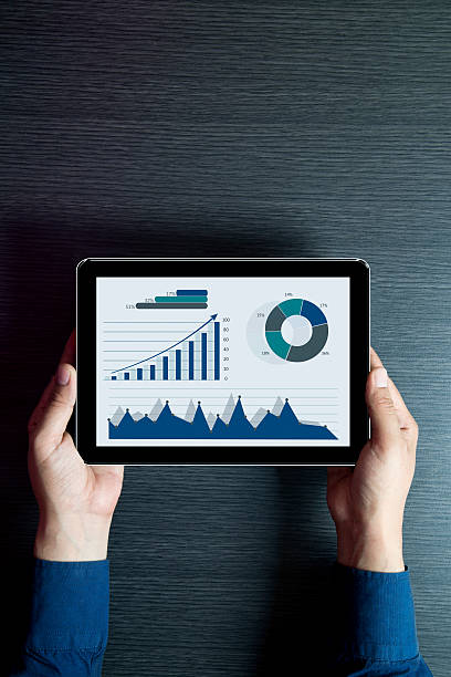 Close-up of a businessman analyzing business graphs on digital tablet. Close-up shot of financial data and statistics.