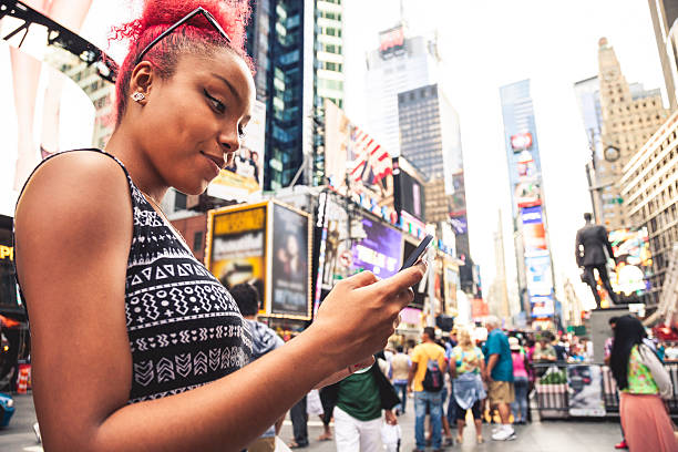 istock Young hispanic woman texting on mobile in Times Square 466581082