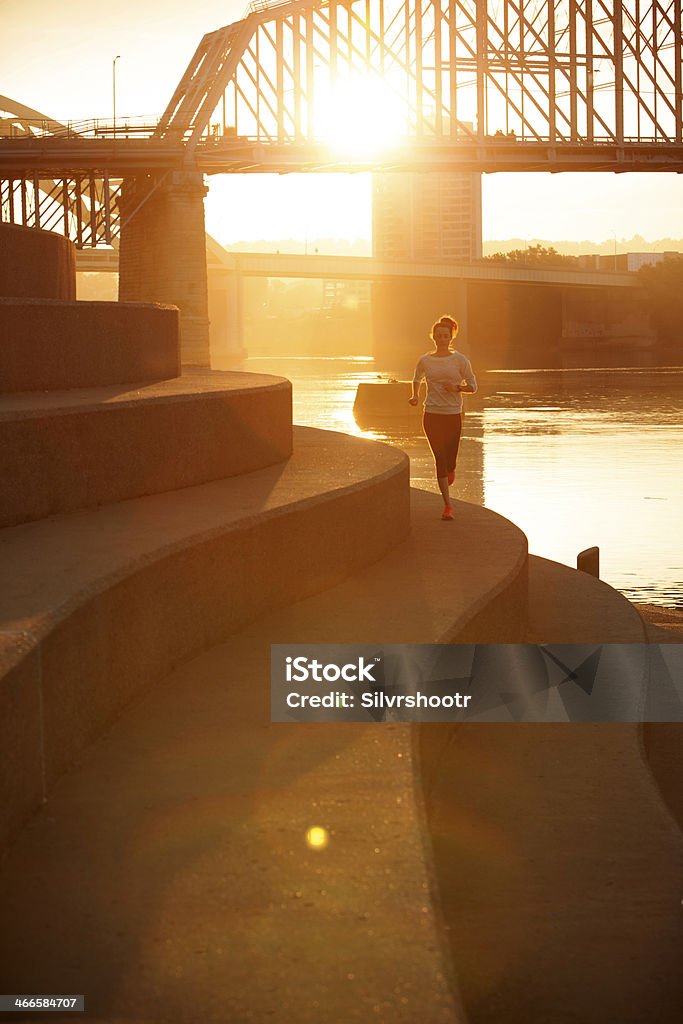 A woman running along the Ohio River during sunrise A fit and attractive woman is on her morning run alongside the Ohio River.  Active Lifestyle Stock Photo