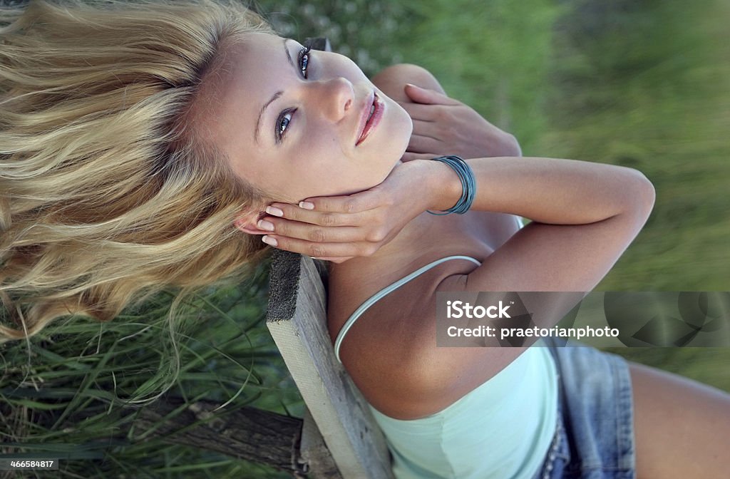 One wonderful day Beautiful blonde girl lying on the bench. Adult Stock Photo