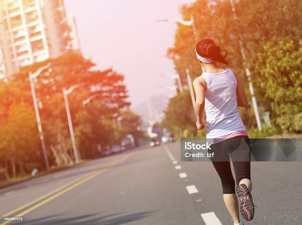 fit sports woman running at asphalt road back of healthy sports woman running at asphalt road Active Lifestyle Stock Photo