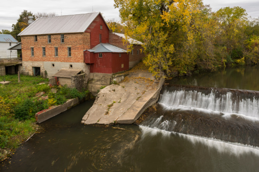 An old mill next to a dam during autumn.