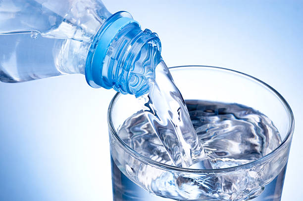 istock Pouring glass of water from plastic bottle on blue background 466588668