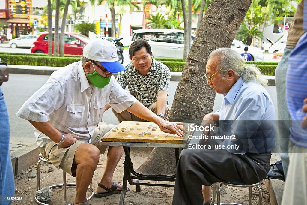 Men playing traditional board game in Saigon, Vietnam. Saigon, Vietnam- November 17, 2013: Unidentified men playing board game  Xiangqi on November 17,2013 in Saigon, Vietnam.Board games have been played in most cultures and societies throughout history. Active Seniors Stock Photo