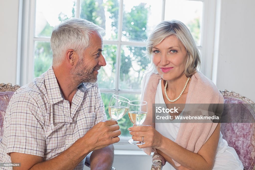 Happy mature couple with wine glasses at home Portrait of happy mature couple with wine glasses at home 2015 Stock Photo